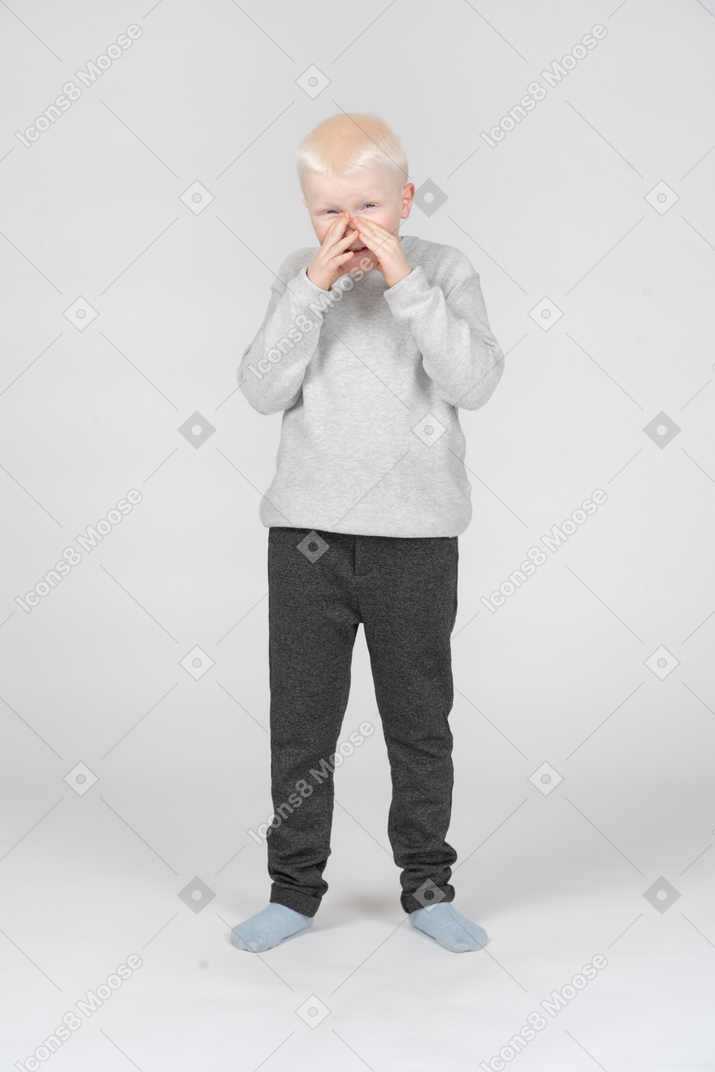 Front view of a boy covering his mouth with hands and laughing