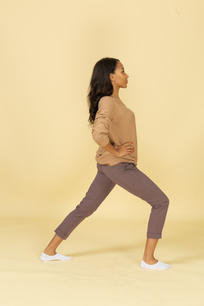 Side view of a squatting dark-skinned young female making a lunge