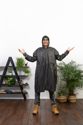 Smiling man in raincoat shrugging and spreading his arms