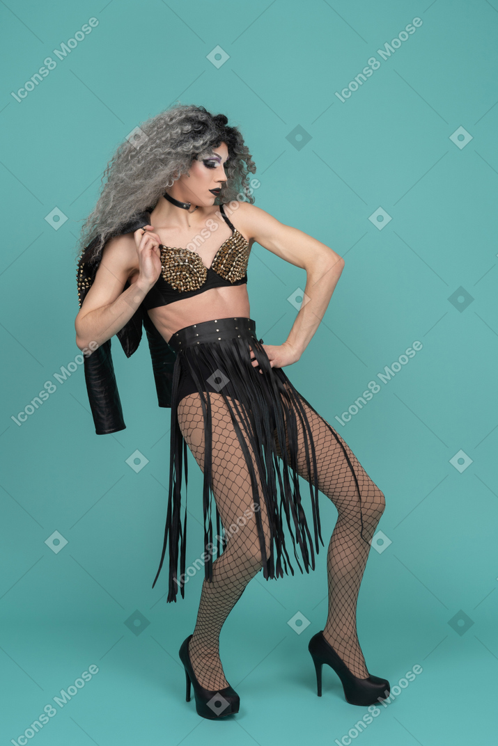 Drag queen in all black outfit posing with leather jacket over shoulder
