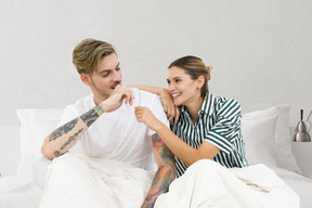 A man and woman sitting on a bed together