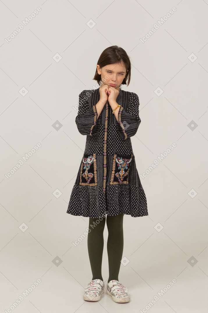 Front view of a scared little girl in dress holding hands together