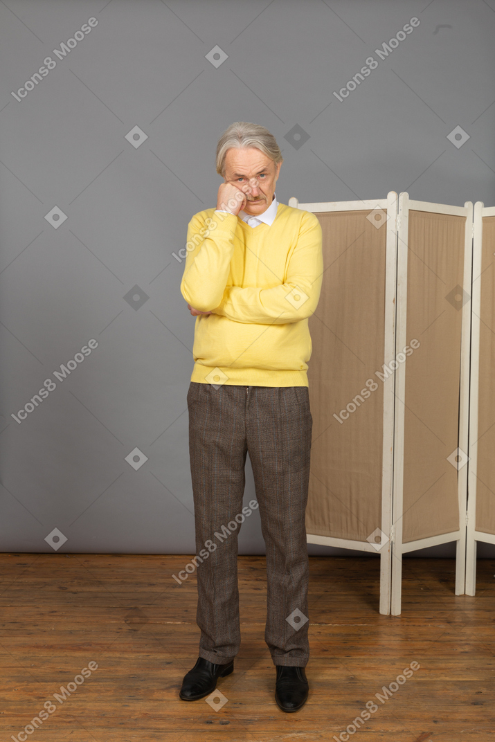 Vista frontal de un anciano pensativo cerca de la pantalla tocando la barbilla