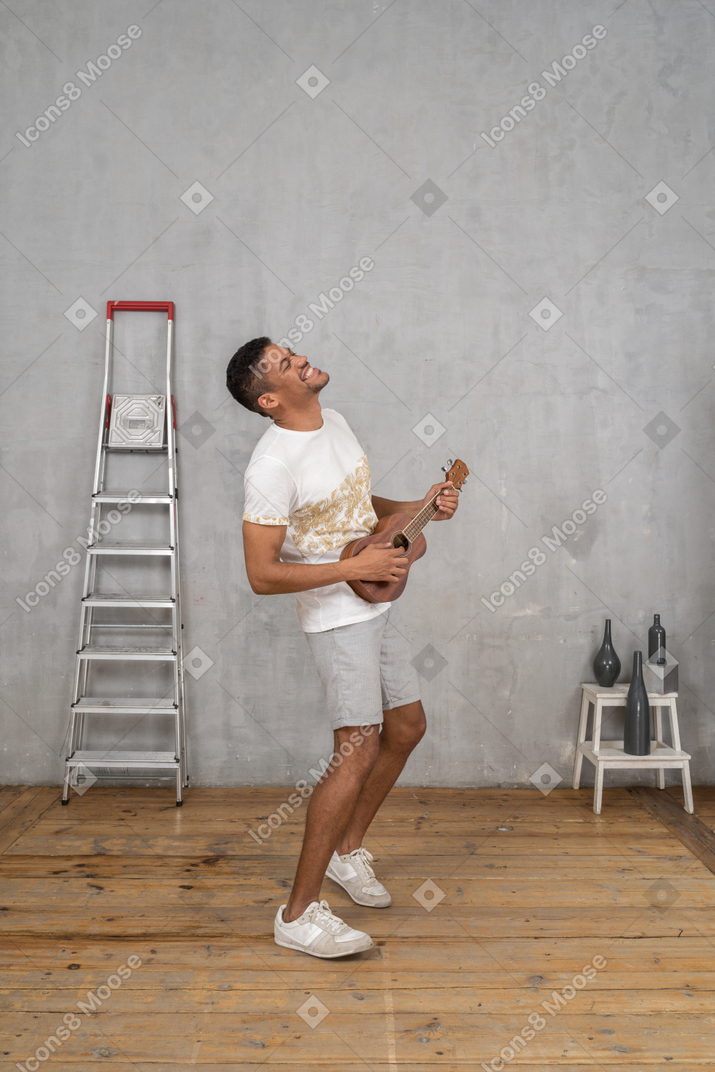 Side view of a man enjoying himself playing ukulele