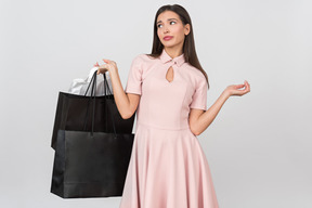 Frustrated young woman holding shopping bags
