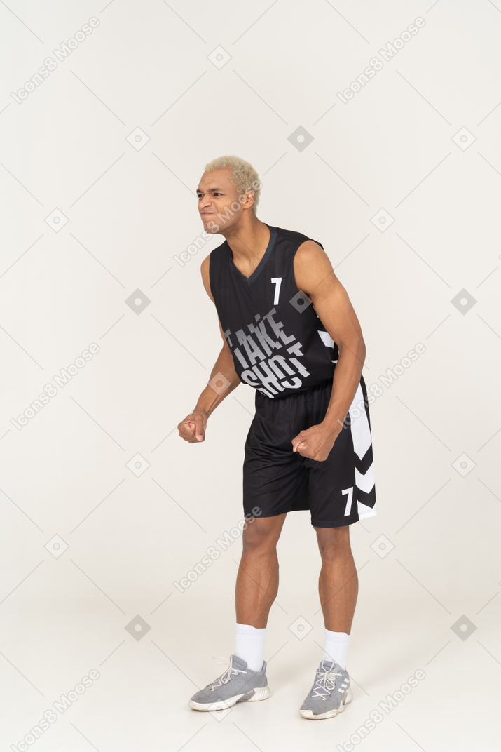 Vista de tres cuartos de un joven jugador de baloncesto masculino enojado inclinado hacia adelante