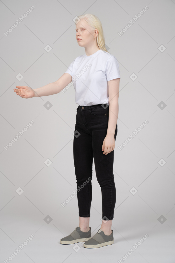 Вид в три четверти на молодую девушку, стоящую и держащую руку