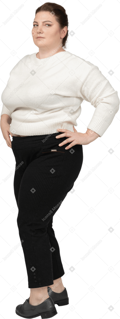 Femme dodue en pull blanc posant avec les mains sur les hanches