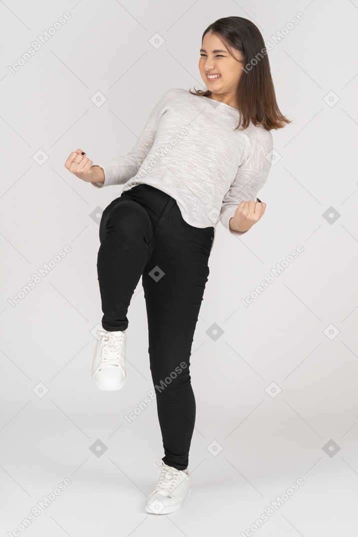Front view of a happy young indian female in casual clothing clenching fists