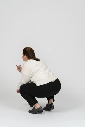 Rear view of a plump woman in casual clothes squatting