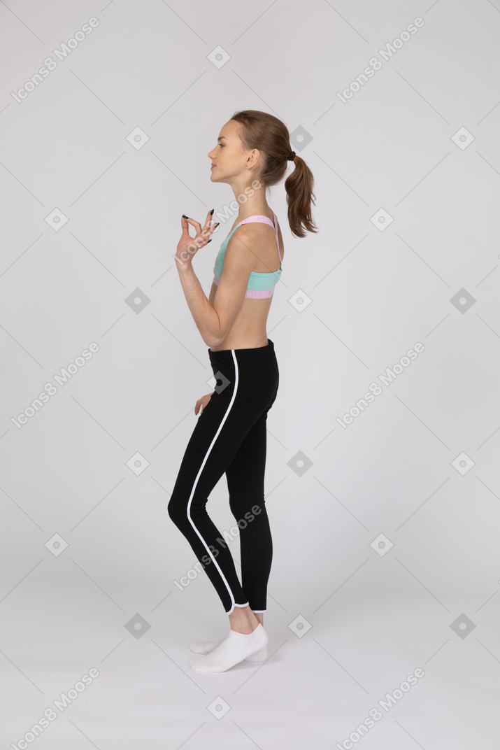 Side view of teen girl showing ok sign