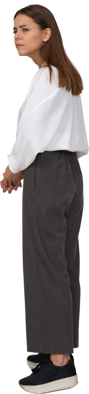 Vista posteriore di tre quarti di una giovane donna in abiti da ufficio che lavora a maglia le sopracciglia
