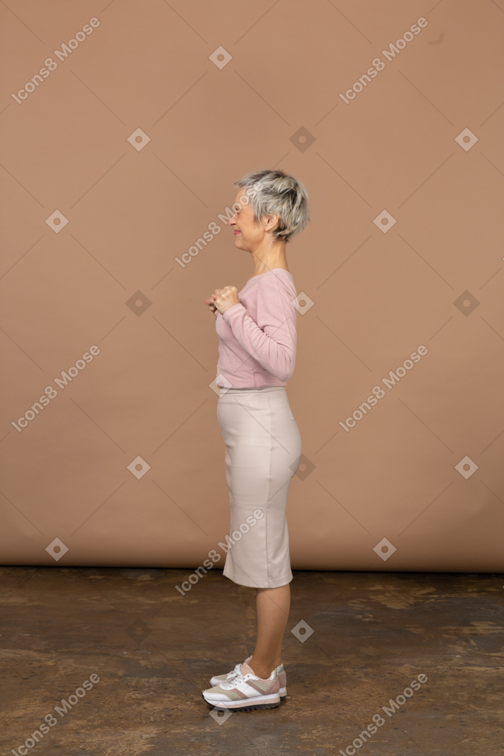 くいしばられた握りこぶしで立っているカジュアルな服を着た幸せな女性の側面図