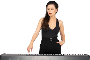 一位年轻的女士，穿着黑色连衣裙，按下钢琴的键的前视图