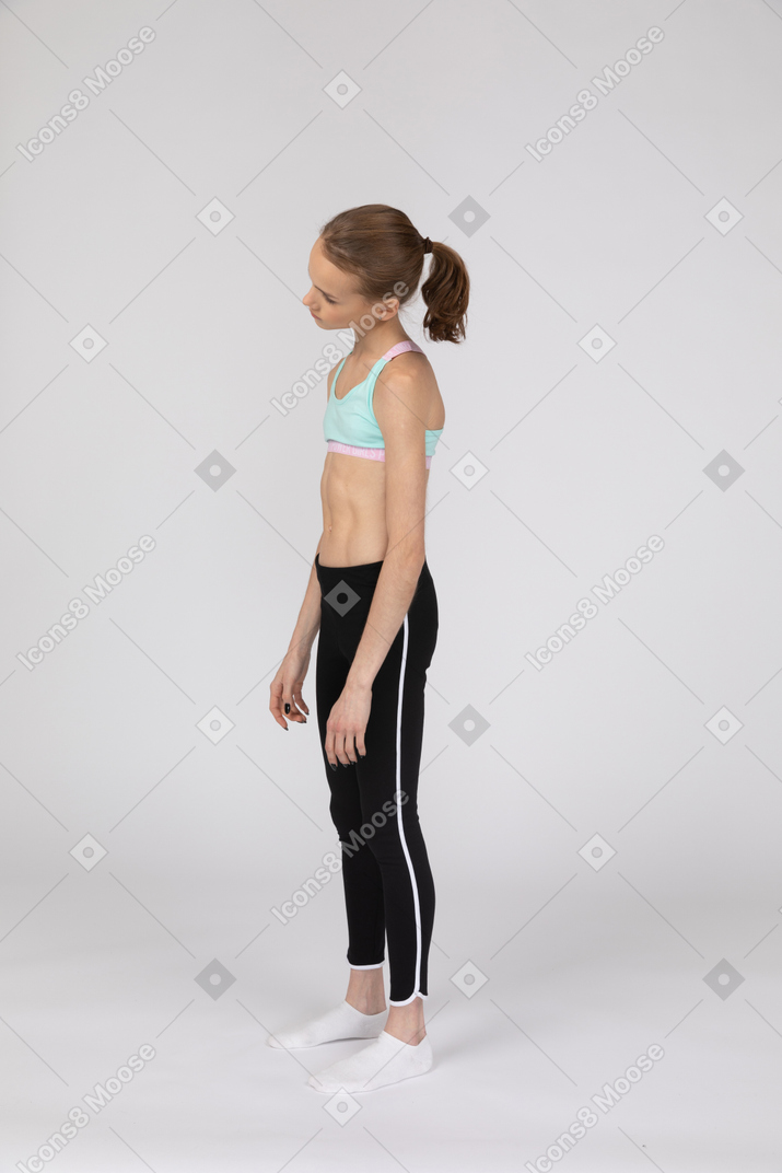 Vista de tres cuartos de una jovencita cansada en ropa deportiva inclinando la cabeza