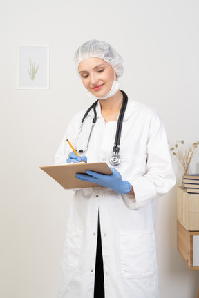 Vista frontale di una giovane dottoressa che prende appunti sul suo tablet
