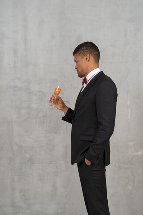 Homem com roupa formal, olhando para uma taça de champanhe
