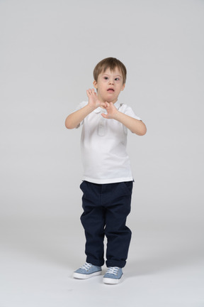 Surprised little boy standing with his hands up