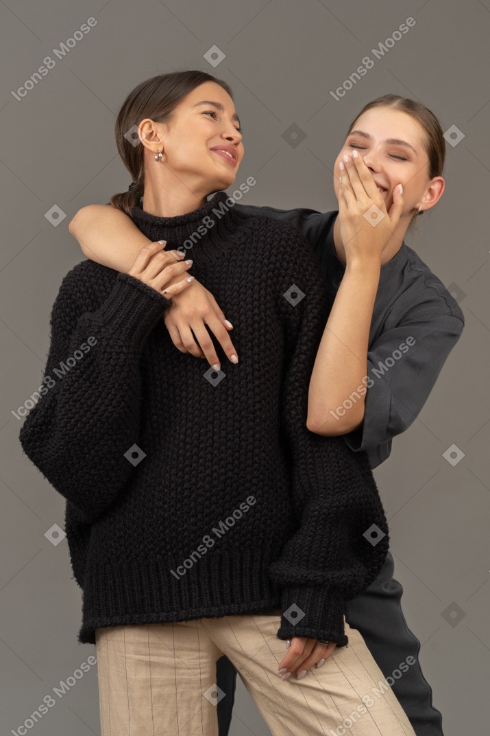 Две женщины обнимаются и смеются