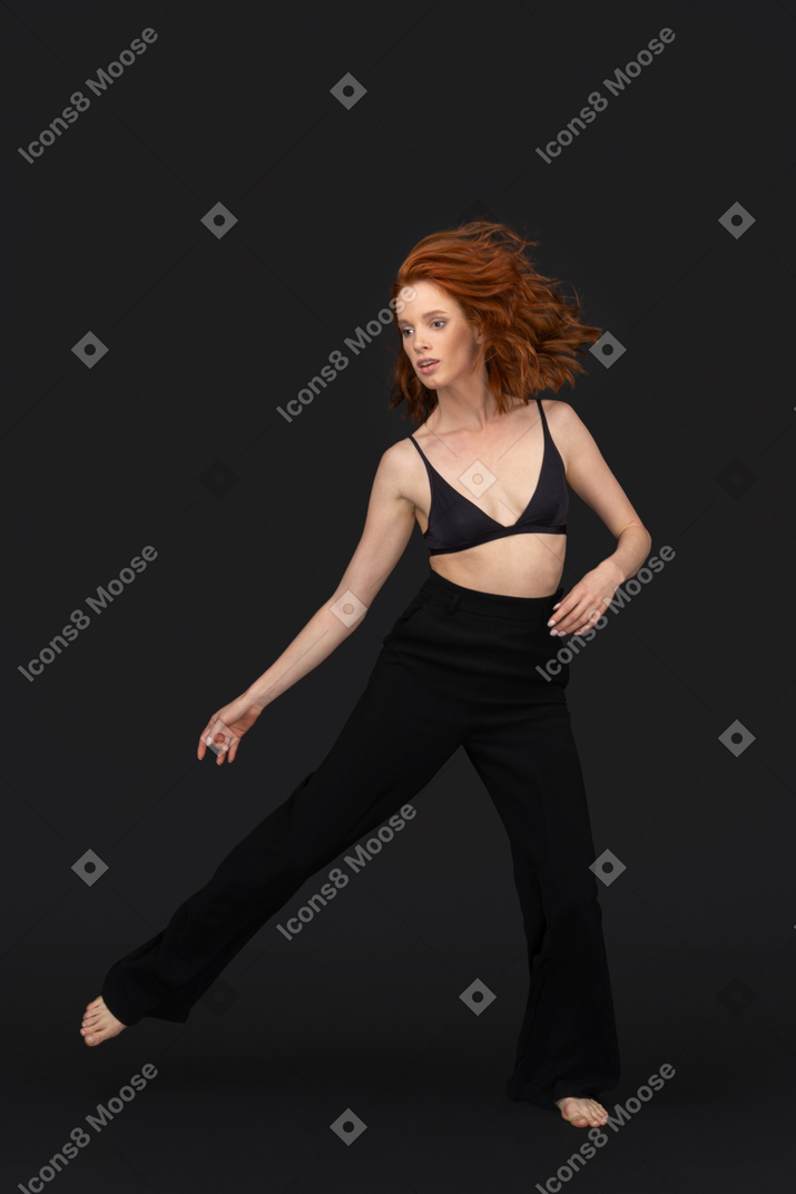 A frontal view of the beautiful woman dressed in black posing on the black background