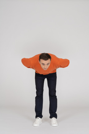 Young man in orange sweatshirt standing