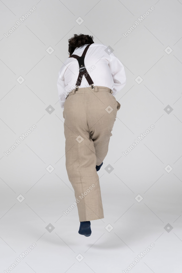 Back view of man in suspenders jumping