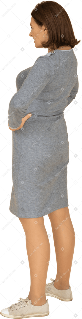 Vue latérale d'une femme en robe grise debout avec les mains sur les hanches