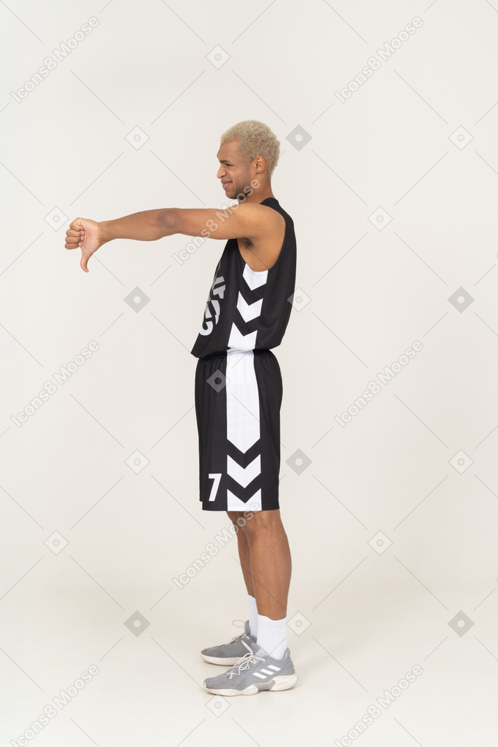 Vista laterale di un giovane giocatore di basket maschile che mostra il pollice verso il basso