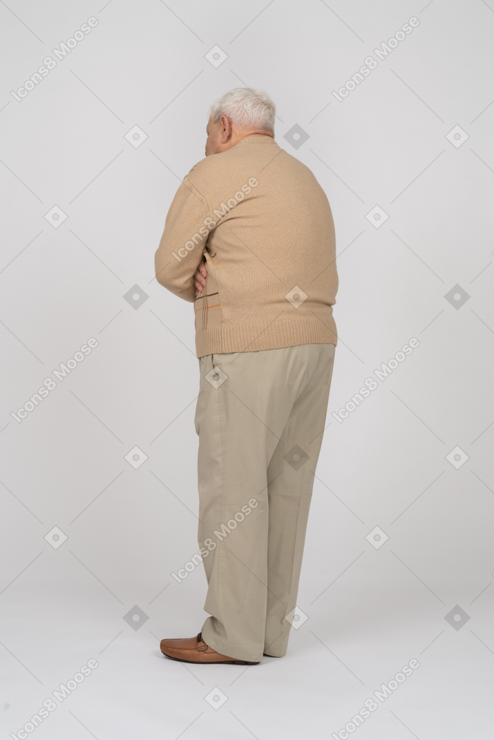 Вид сбоку на старика в повседневной одежде, стоящего со скрещенными руками