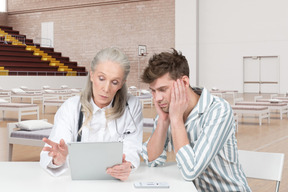 Sad man and doctor looking at tablet
