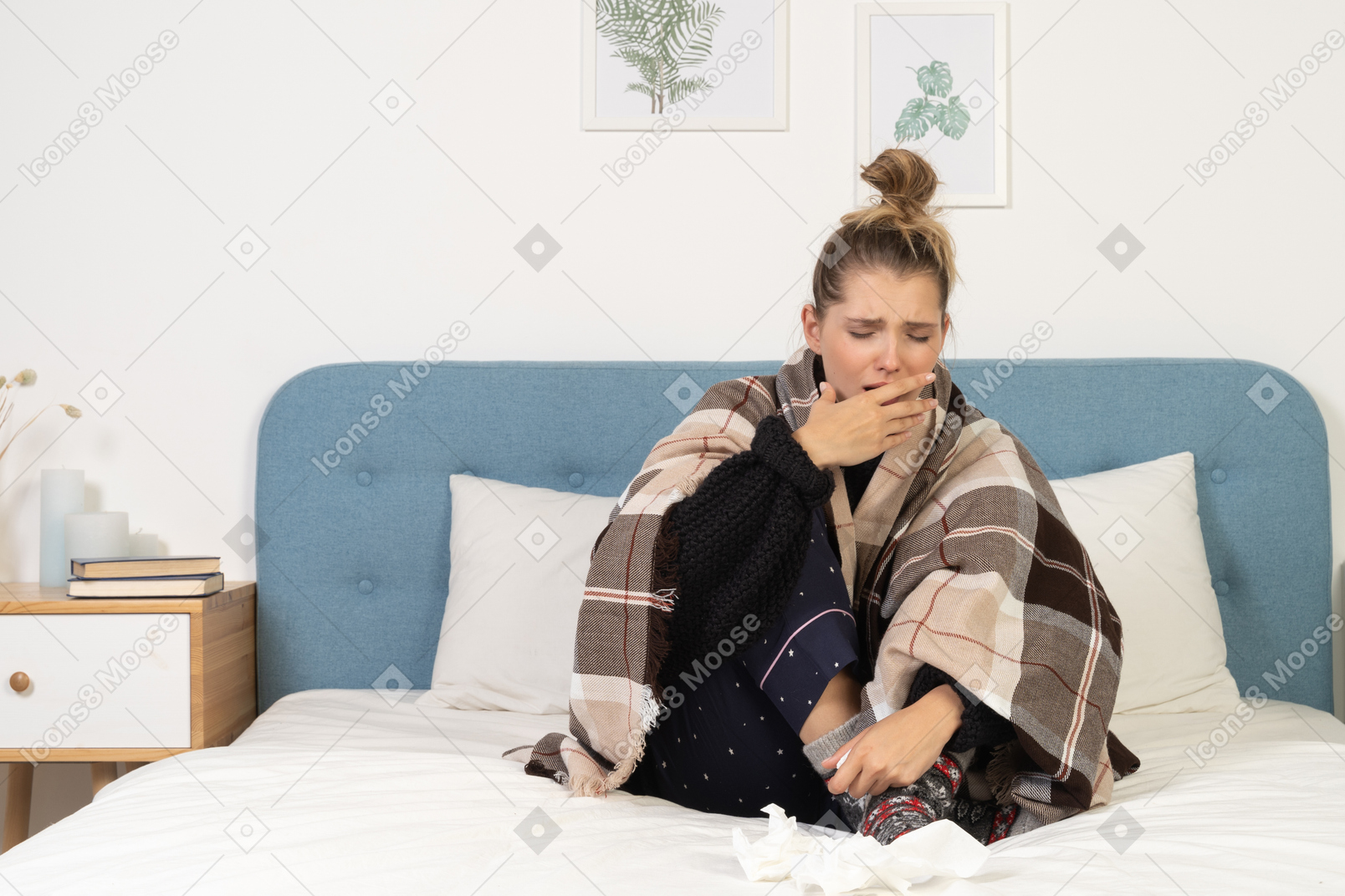 Front view of an ill coughing young lady in pajamas wrapped in checked blanket in bed