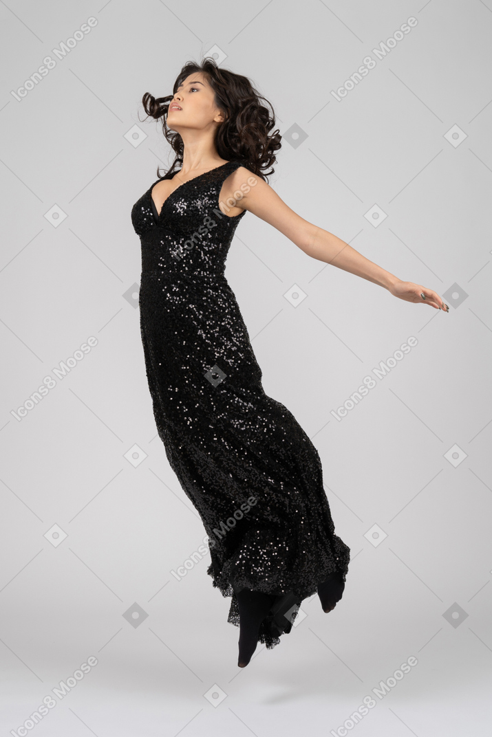 Saltos de mulher bonita no vestido preto