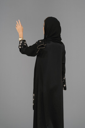 Covered arab woman standing back to camera