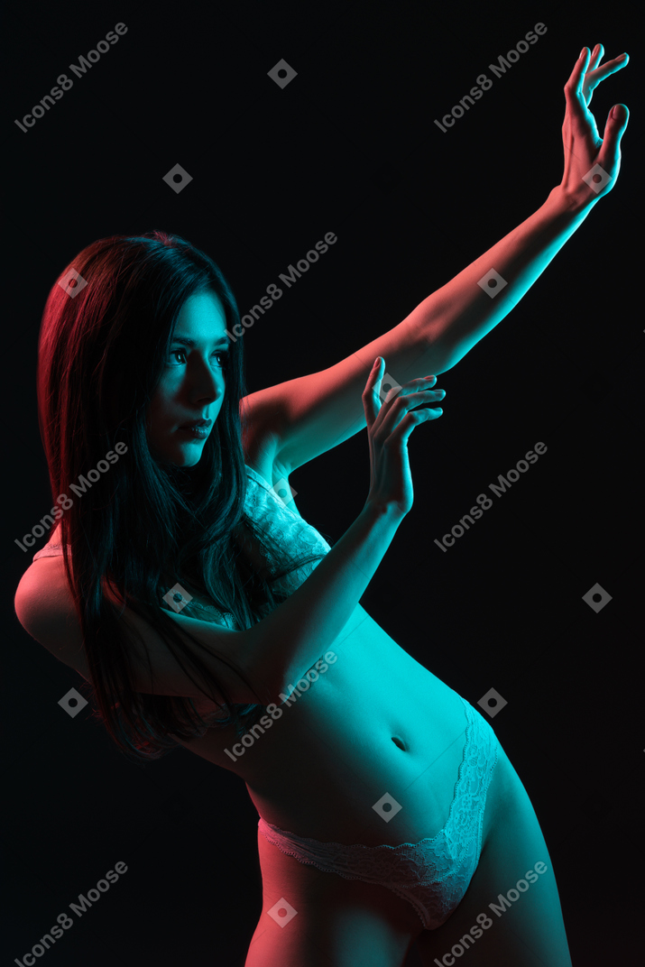 Primo piano una giovane donna gesticolando vestita in biancheria intima nel buio