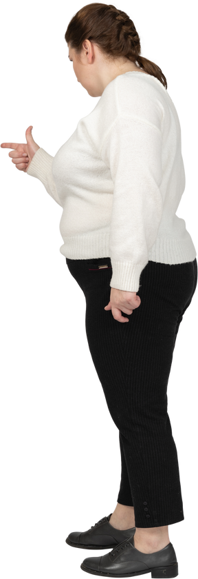 Vista lateral de uma mulher rechonchuda em roupas casuais apontando com um dedo