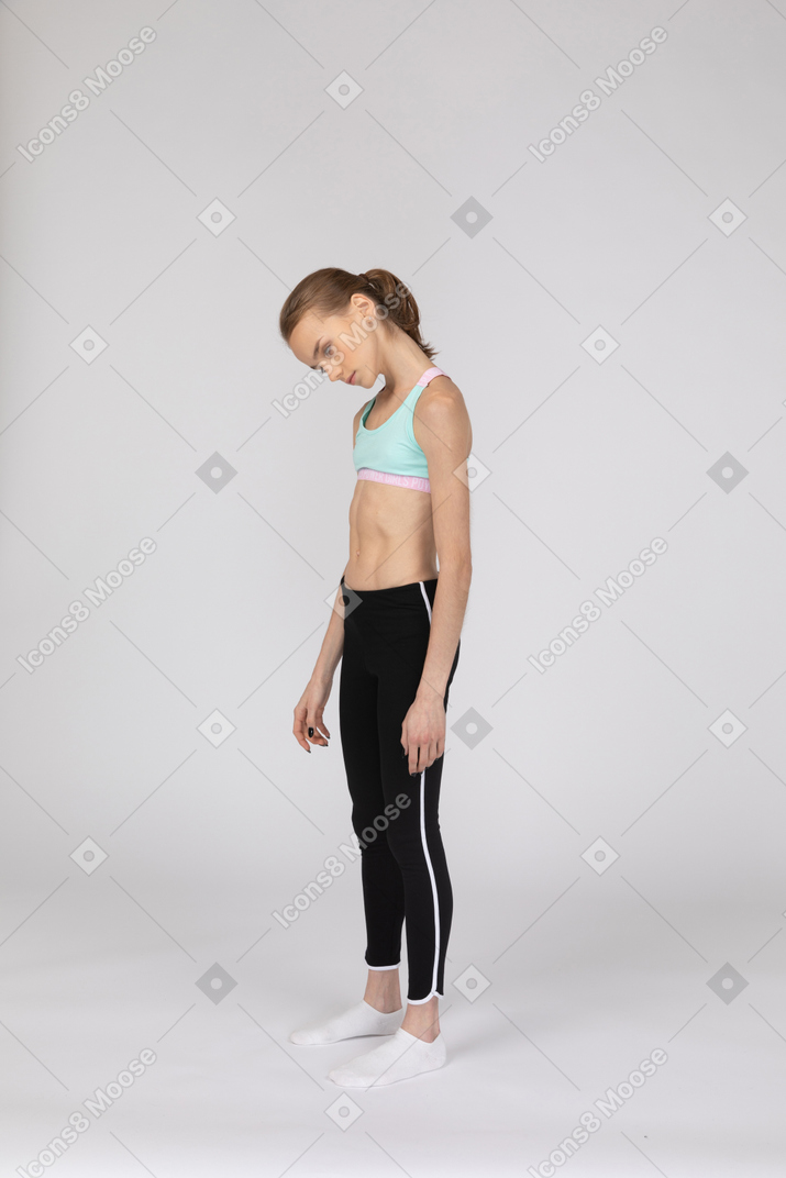 Vista de tres cuartos de una adolescente cansada en ropa deportiva inclinando la cabeza y poniendo los ojos en blanco