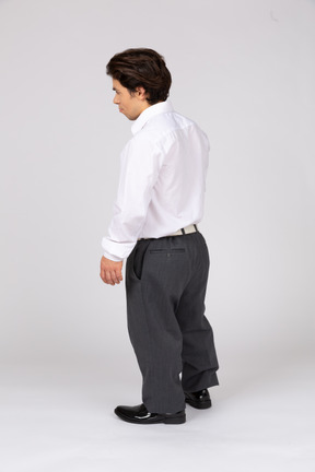 Вид сзади в три четверти на мужчину в формальной одежде, отводящего взгляд