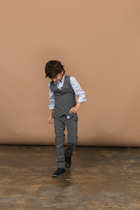 Vista frontal de un niño con traje caminando hacia adelante