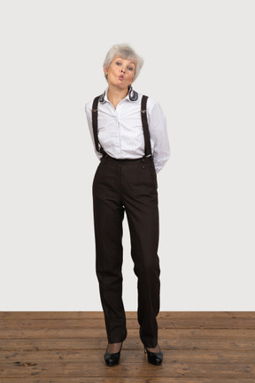 Front view of a pouting old lady in office clothing leaning forward