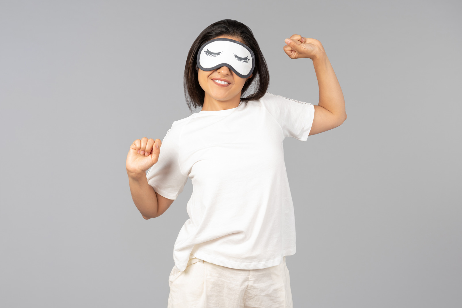 Young indian woman in comfy clothes and sleeping mask stretching arms