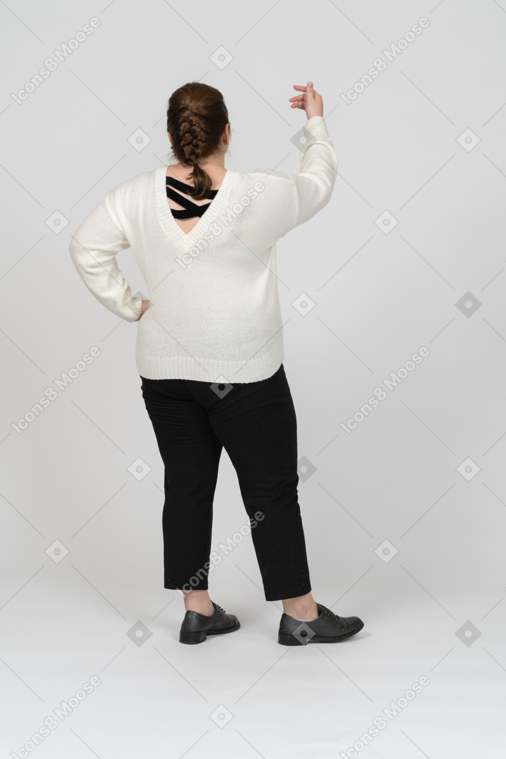 Rear view of a plus size woman in casual clothes with raised hand