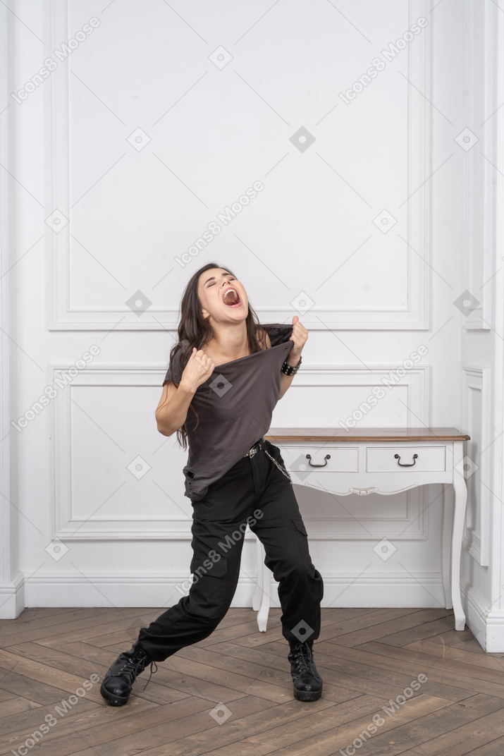 Three-quarter view of a screaming female rocker tearing up her t-shirt