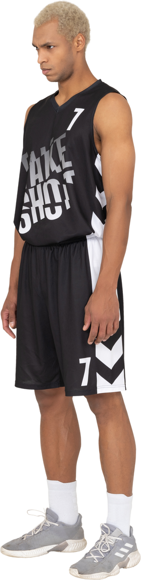 Vue de trois quarts d'un jeune joueur de basket-ball masculin debout, la tête baissée