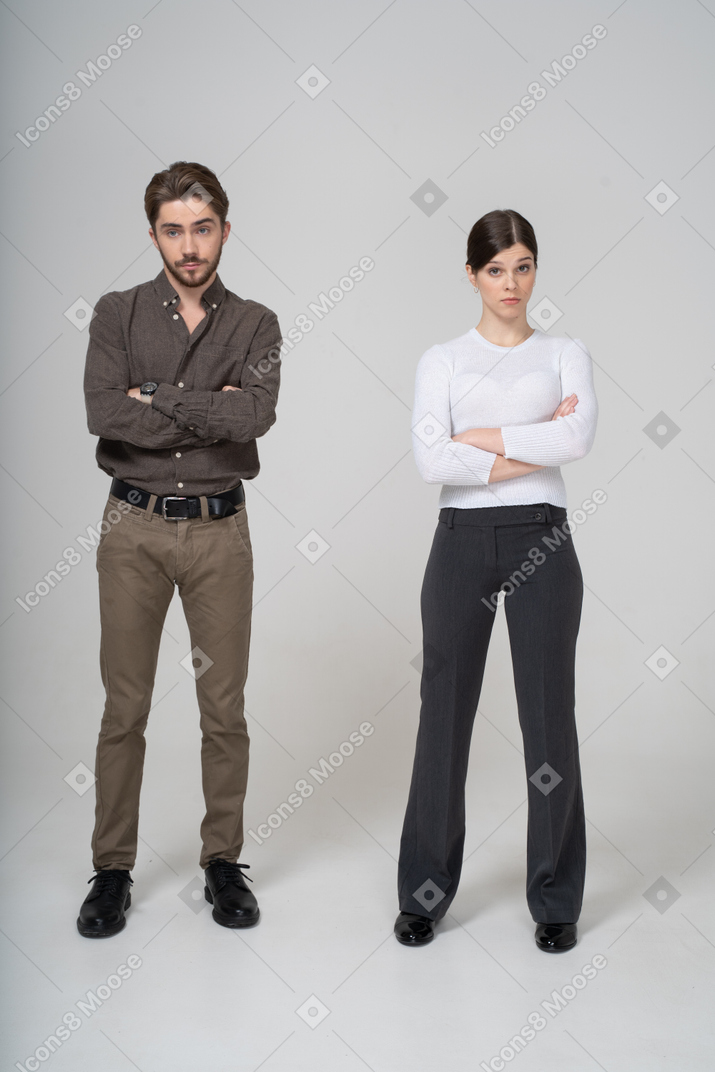 Front view of a young couple in office clothing crossing arms