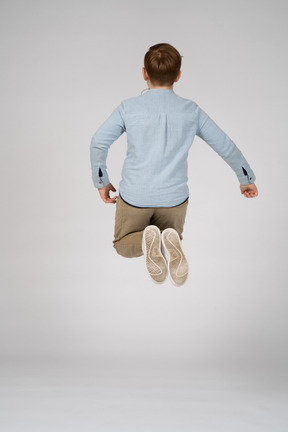 Back view of a boy in casual clothes and white sneakers jumping