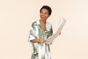 Black short-haired woman in a white and green dress, standing with a map in her hands