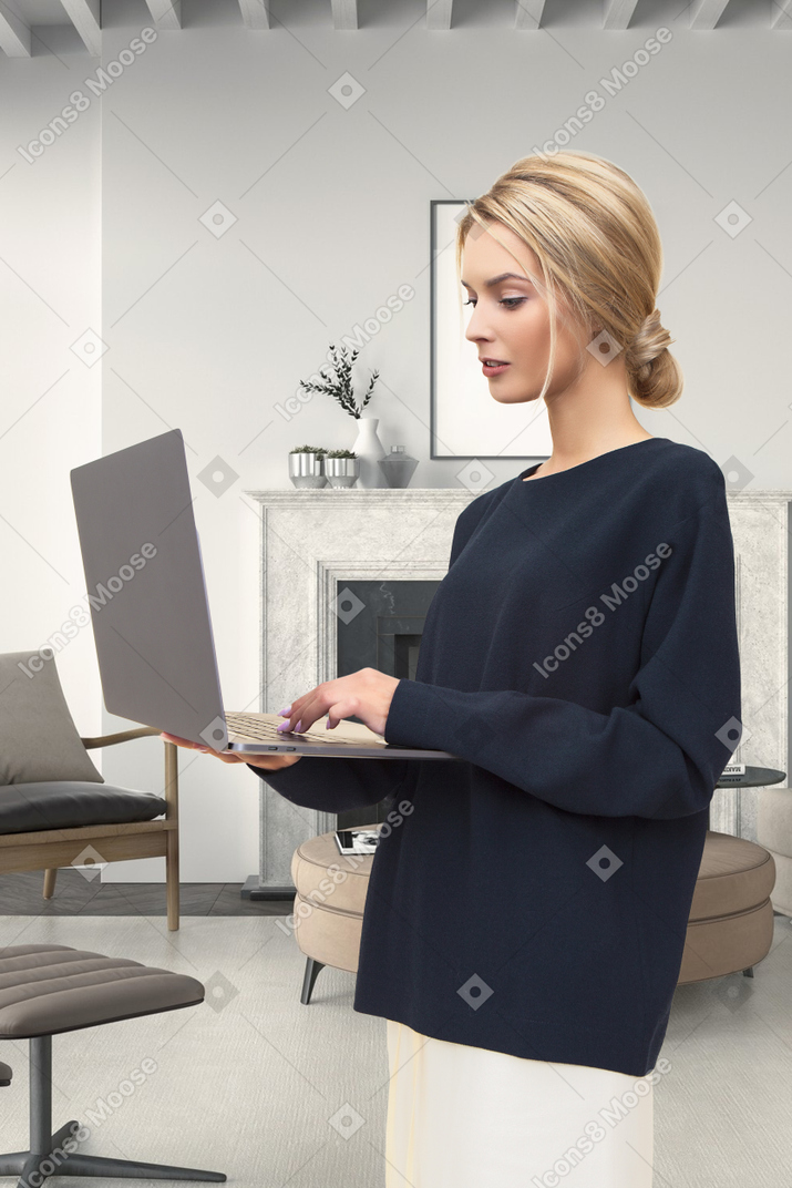 A woman standing in a living room using a laptop computer