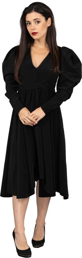 一位年轻的女士穿着一件黑色的连衣裙，手牵着手的前视图