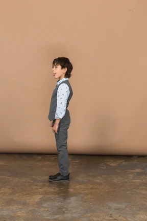 Cute boy in grey suit standing in profile