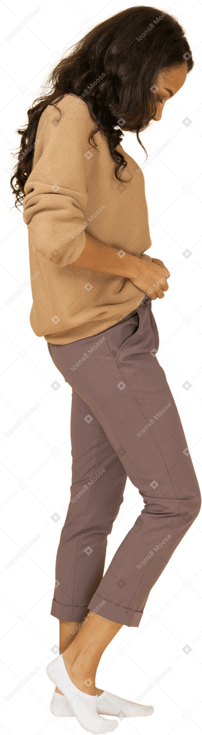 Vista lateral de uma jovem mulher de pele escura fechando o zíper das calças